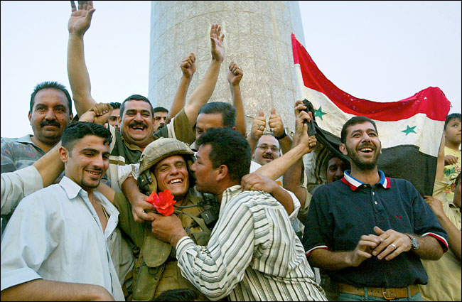 In front of the Palestine Hotel, Iraqis jubilant at the coalition's victory over Saddam Hussein, hug Lance Cpl. Shawn Hicks , Baghdad, April 9, 2003.
